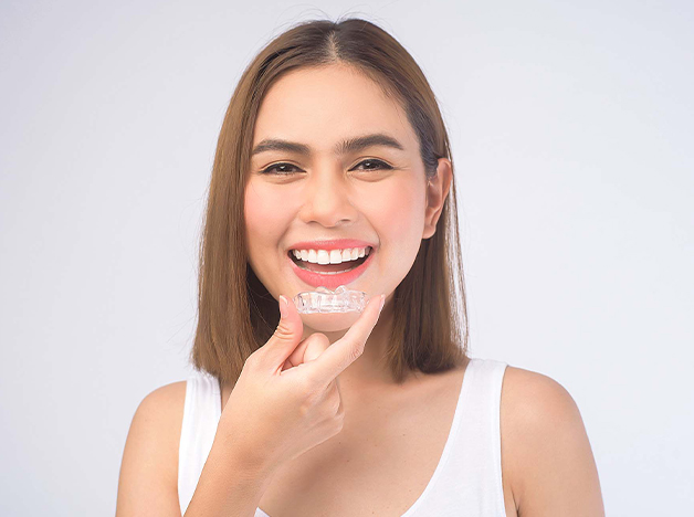 Gresham Advanced Dentistry – Invisalign for Teens Teen holding an Invisalign clear aligner in Gresham, OR