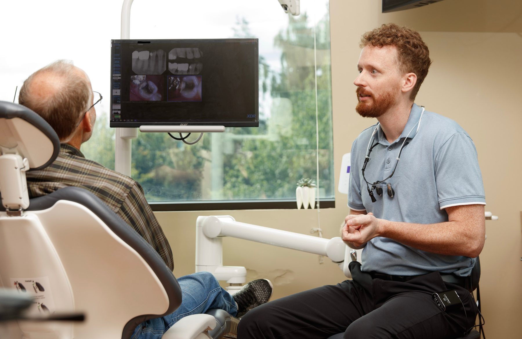 gad-awb-dr-hanset-patient-consult Dr. Isaac Hanset talking with a patient beside digital X-rays on the treatment-room screen