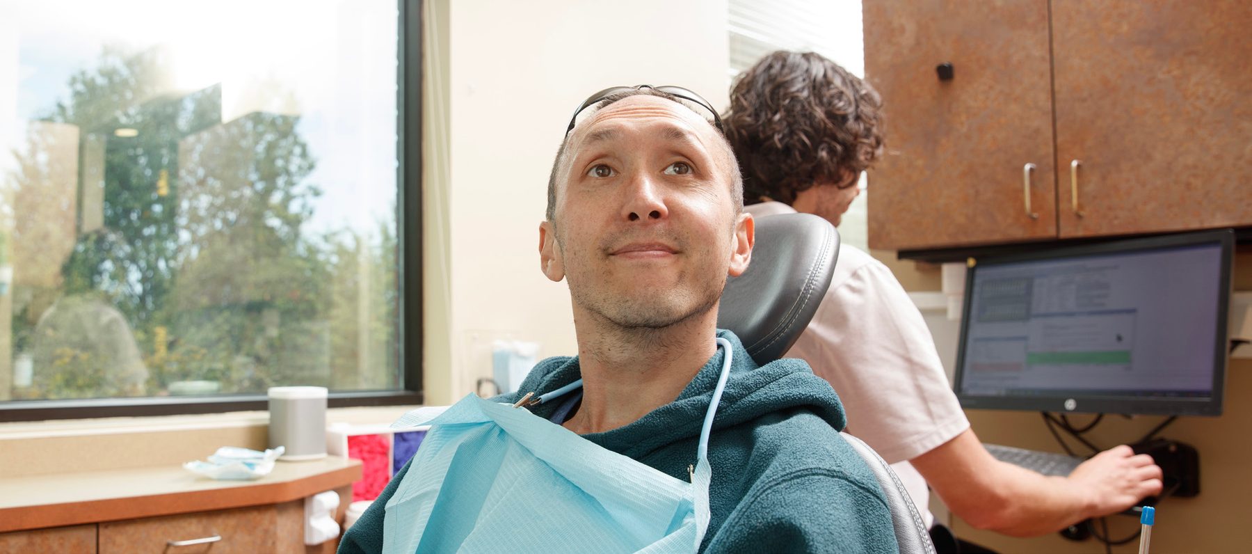 gad-awb-patient-in-dental-chair Patient relaxing in the dental chair while a team member works at the computer
