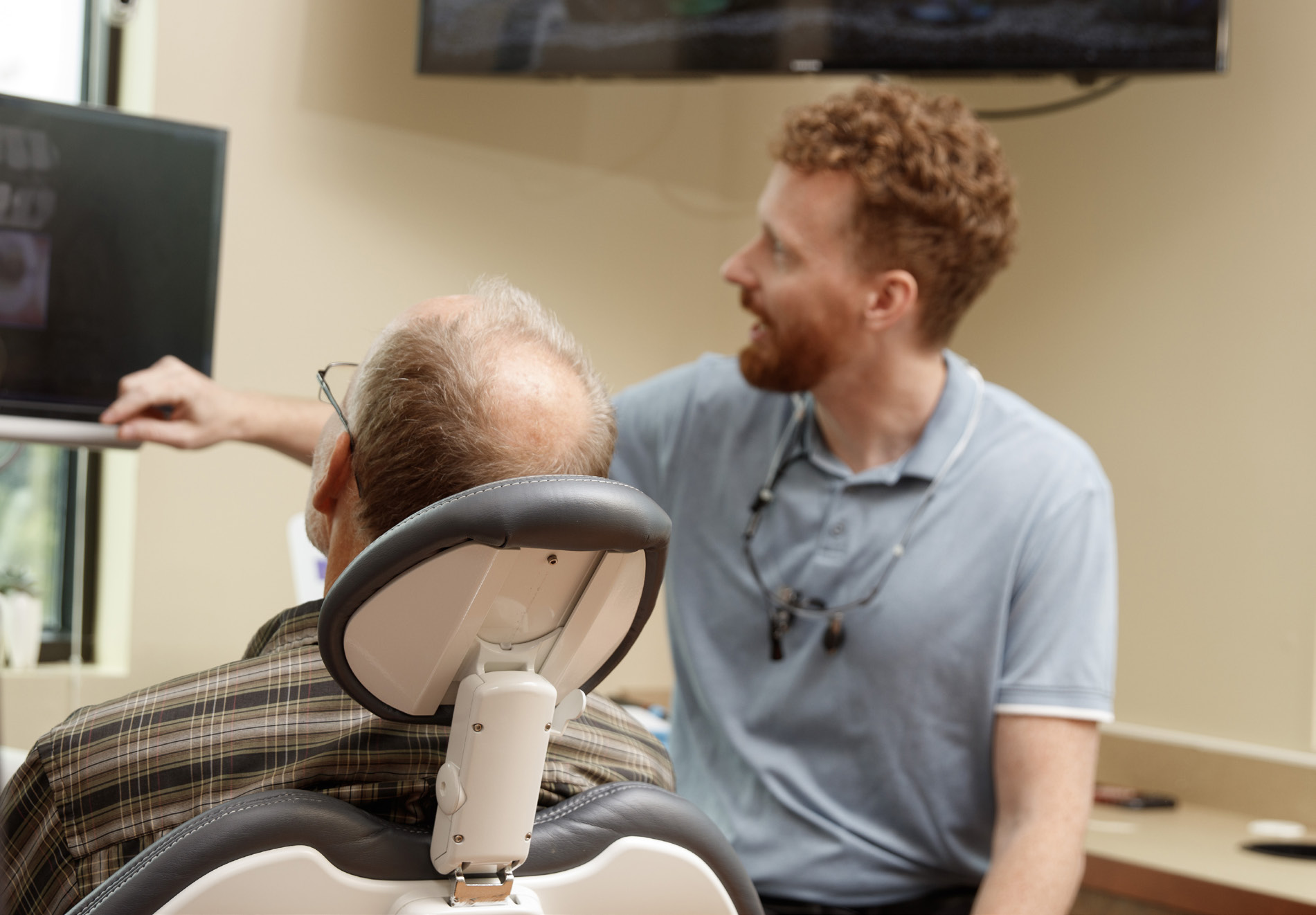 Dentist talking a seated patient through images on a screen