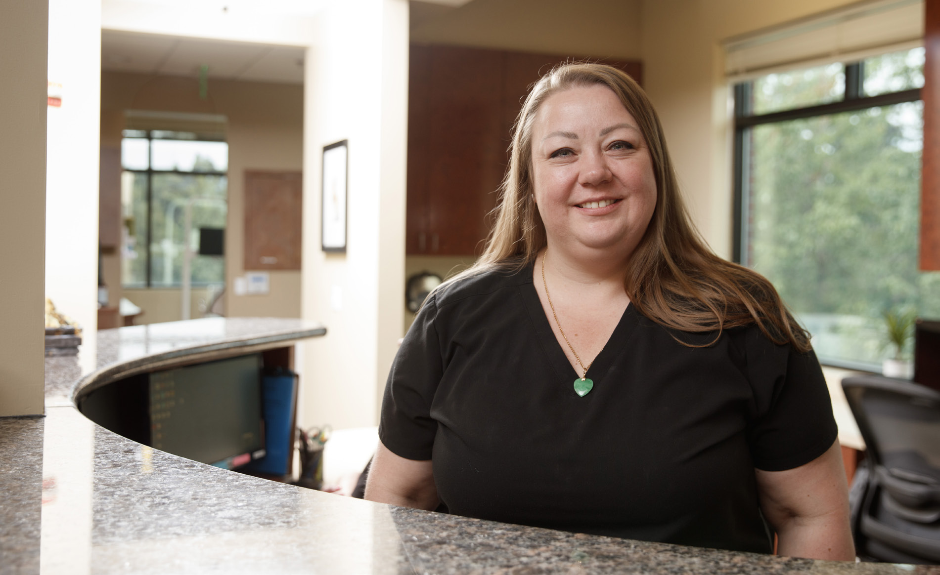 Smiling Gresham Advanced Dentistry team member at the reception desk